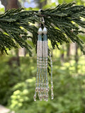 Pearl and crystal tassel earrings hanging from a cedar branch